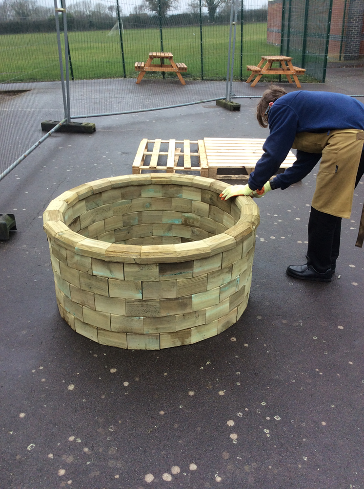 pupil does the finishing touches to the circular raised bed